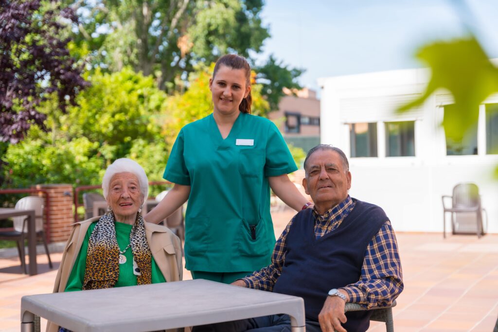 elderly couple and a nurse standing in front of a nursing home