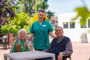 elderly couple and a nurse standing in front of a nursing home