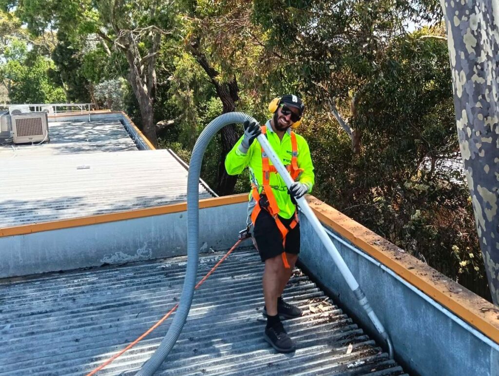 smiling man vacuuming commercial roof gutter