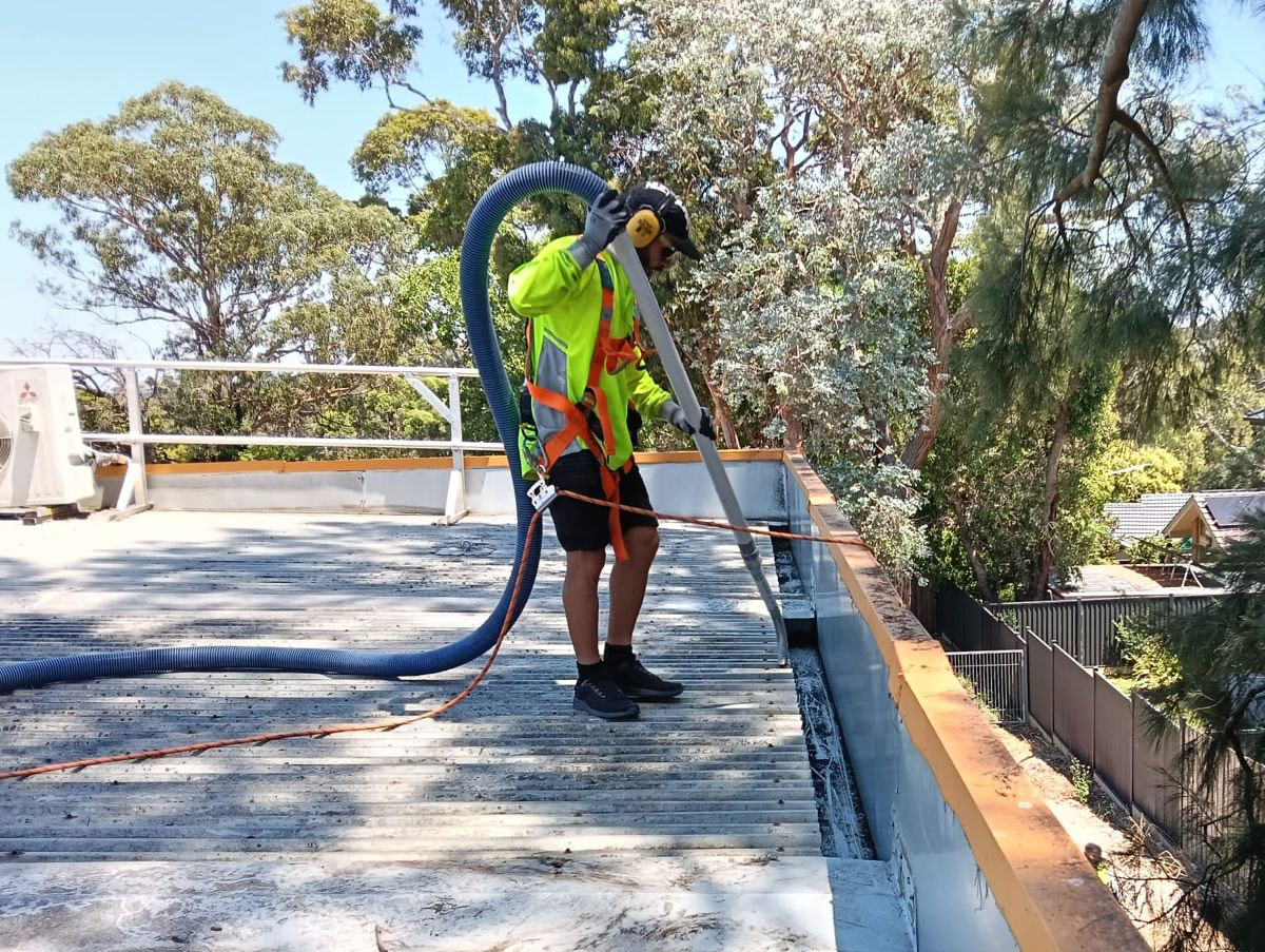 man using vacuum gutter with safety harness